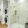 glassed in walk-in shower in bright bathroom with stacked washer/dryer niche